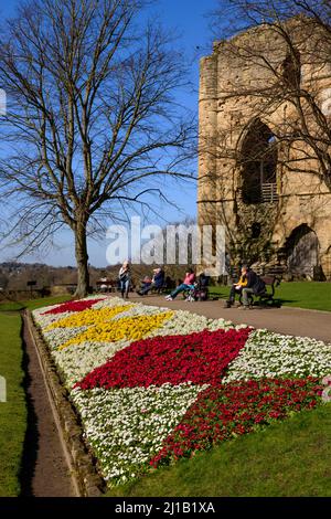 Menschen sitzen entspannt Sonne genießen (helle Border Blumen, alten Turm halten Ruinen, blauer Himmel) - Knaresborough Castle, North Yorkshire, England, Großbritannien. Stockfoto