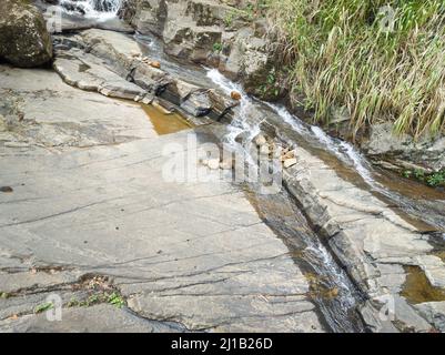 Strom fließt durch Felsen, engen Fluss oder Fluss von Wasser auf einer felsigen Oberfläche Stockfoto