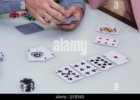 Die Hände des Mannes mischen Karten. 2 Asse auf dem Tisch in einem Pokerspiel mit Chips, Karten auf dem Tisch. Genießen Sie den Moment, digitale Entgiftung mit Freunden. Lebst Stockfoto