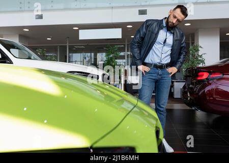 Ein Mann in einem Autohaus wählt einen Sportwagen für sich Stockfoto