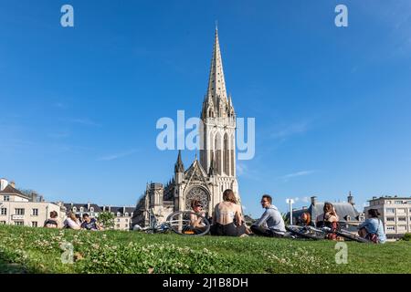 GRUPPE JUNGER MENSCHEN AUF DEM BURGGARTEN VOR DER SAINT-PIERRE-KIRCHE, CAEN, CALVADOS, NORMANDIE, FRANKREICH Stockfoto