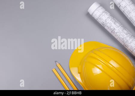Hut (Helm), Projektzeichnungen Rolle und Bleistifte, auf grauem Hintergrund. Reparatur- und Konstruktionskonzept. Flach liegend, Draufsicht Bild, Stockfoto
