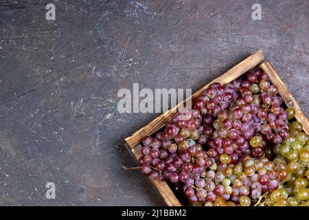 Holzkiste voller Trauben auf dunklem Hintergrund. Flachlagerung, Draufsicht mit Kopierplatz. Stockfoto