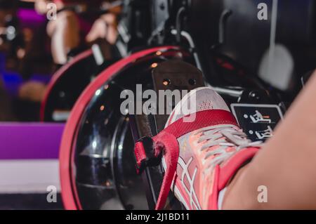 Nahaufnahme des Fußes auf dem Stand eines Rudergeräts vor dem Spiegel in einer Turnhalle, Kopierraum, Sportkonzept. Stockfoto