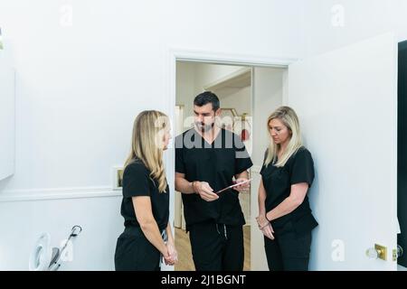 Ein Arzt in einer medizinischen Spa- und Wellness-Klinik, der mit zwei Krankenschwestern spricht Stockfoto