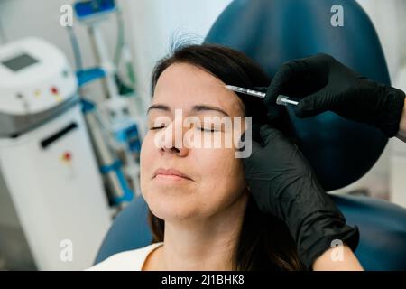 Nahaufnahme einer Frau, die Botulinumtoxin oder Füllstoffe auf Stirn und Gesicht bekommt Stockfoto