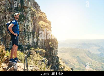 Die natürliche Schönheit der Welt genießen. Aufnahme eines jungen Mannes, der die Aussicht von der Spitze eines Berges bewundert. Stockfoto