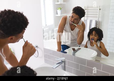 Spiegelreflexion von hispanischen Vater und Sohn, die im Badezimmer die Zähne putzten Stockfoto