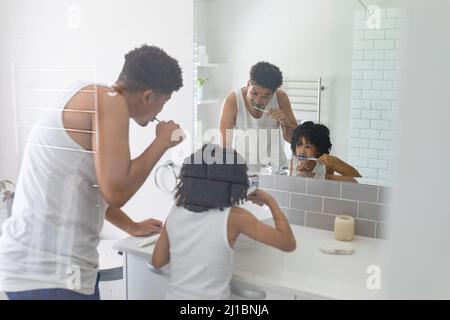 Hispanischer Vater und Sohn putzten sich im Badezimmer vor dem Spiegel die Zähne zusammen Stockfoto