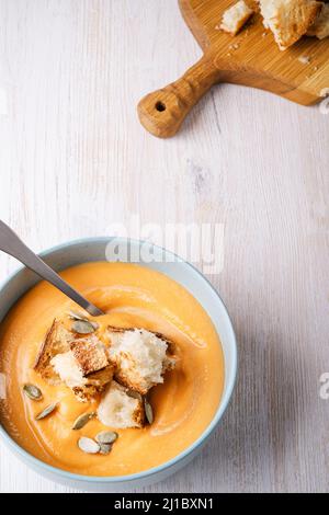 Butternut-Kürbissuppe mit geröstetem Brot auf hellem Holzhintergrund, herbstlich gemütliches vegetarisches Gericht, Draufsicht Stockfoto