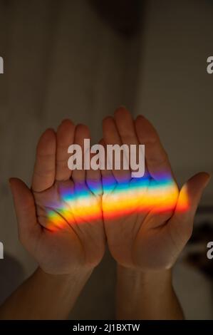 Regenbogenstrahl auf der Hand einer Frau. Stockfoto