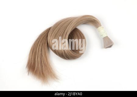 Haarprobe für Erweiterung aufgerollt, blonde Farbe. Weißer Hintergrund. Stockfoto