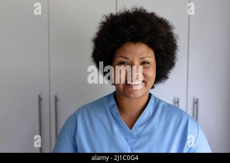 Porträt einer lächelnden afroamerikanischen Krankenschwester mit mittlerem Erwachsenen, die im Krankenhaus gegen den Schrank stand Stockfoto