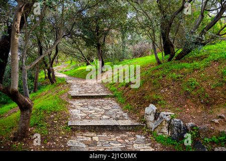 Der schattige Steinwanderweg und Pfad auf dem Philopappos-Hügel zum Denkmal im historischen Zentrum von Athen, Griechenland. Stockfoto