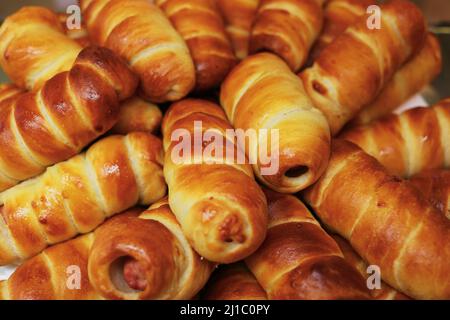 Wurst in Teig oder Hotdog Nahaufnahme. Viele frische Backwaren aus Blätterteig und Wurst. Draufsicht. Hintergrund für Bäckerei oder Fast-Food-Café. Stockfoto