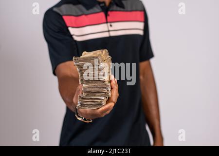 afrikanischer Mann, der ein Paket mit einem nigrischen Naira-Währungsgeld hält Stockfoto