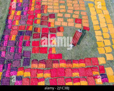 Narayanganj, Dhaka, Bangladesch. 24. März 2022. Tausende von bunten Tüchern werden zum Trocknen unter der heißen Sonne ausgelegt. Nachdem der Stoff gefärbt wurde, werden sie auf einem etwa 10.000 Quadratfuß großen Feld im Batik Village in Narayanganj, Bangladesch, verteilt. Sobald sie trocken sind - was normalerweise vier Stunden dauert - werden sie zu Kleidung gemacht, die weltweit verkauft wird. (Bild: © Mustasinur Rahman Alvi/ZUMA Press Wire) Stockfoto
