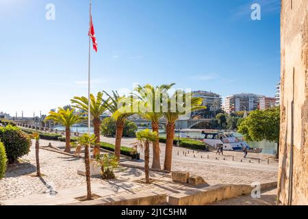 Ein sonniger Tag am Guadalquivir-Fluss in Sevilla, Spanien, mit Palmen entlang der Uferpromenade und Booten im Fluss. Stockfoto