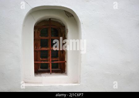 Fenster in einer Nische an der verputzten Wand der Kirche Johannes des Täufers in der Stadt Weliki Nowgorod. Aus der „Window of the World“-Serie. Stockfoto