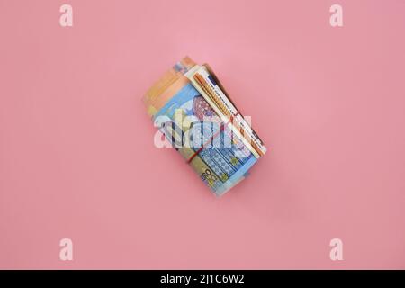 Rolle der Euro-Banknoten. 100 Euro mit rotem Gummiband auf rosa Hintergrund. Unternehmen, Finanzen, Währung Stockfoto