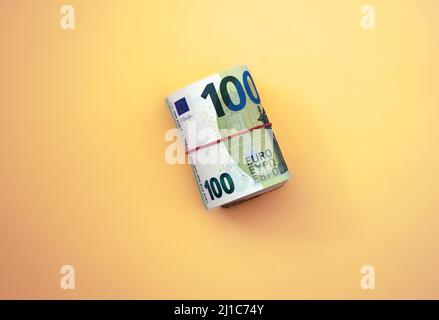 Rolle der Euro-Banknoten. 100 Euro mit rotem Gummiband auf gelbem Hintergrund Stockfoto