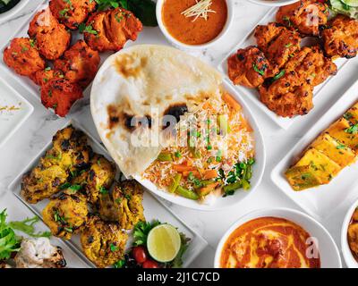 Verschiedene berühmte indische und pakistanische Speisen Tisch Gemüse Biryani, Butter Chicken, Paneer Chicken Tikka Boti Kebab, Limette, Kali Mirchi, Tomatensauce, r Stockfoto