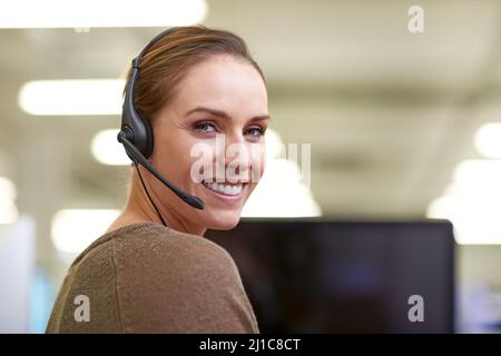 Sie macht den Alltag zu einem glücklichen Tag. Eine attraktive Arbeitnehmerin, die ein Headset trägt. Stockfoto
