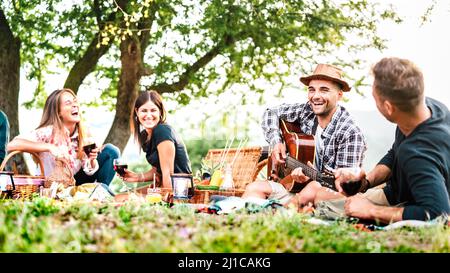 Friends Group hat Spaß Moment bei pic nic spielen Gitarre bei Sonnenuntergang - Freundschaft Lifestyle-Konzept mit jungen Menschen genießen den Frühling zusammen Stockfoto