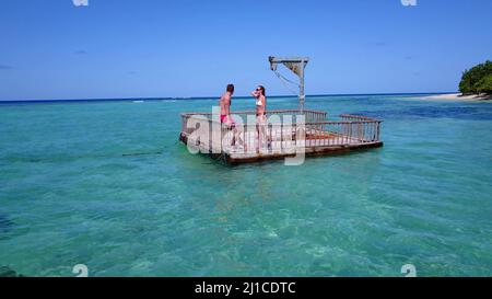 Ein junges Paar, das sich auf einem Ponton-Boot im Meer, auf der Insel Rasdhoo, den Malediven, sonnt Stockfoto