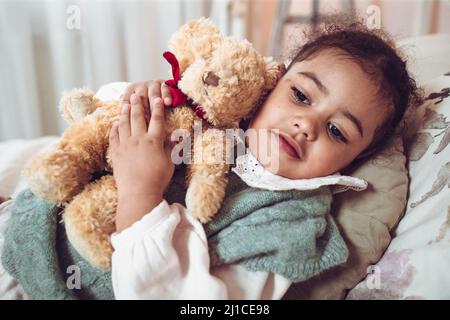 Liebenswert multiethnisch kleines Mädchen umarmt ihren Bären Stockfoto