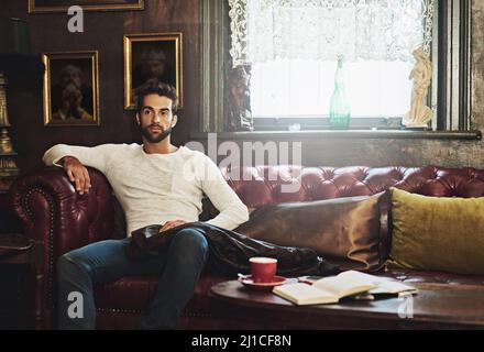 Hes hat ein Deja-Gebräu. Aufnahme eines durchdachten Mannes, der sich auf einem Sofa in einem Café entspannt. Stockfoto