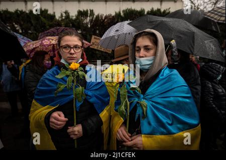 Madrid, Spanien. 24. März 2022. Zwei Frauen, die Sonnenblumen tragen und ukrainische Flaggen tragen, sind bei einem Protest vor der russischen Botschaft von Madrid zu sehen. Nach einem Monat der Invasion versammelten sich Menschen, um gegen die russische Invasion in der Ukraine zu protestieren und Sonnenblumen, das Symbol der Ukraine, zu tragen. Quelle: Marcos del Mazo/Alamy Live News Stockfoto