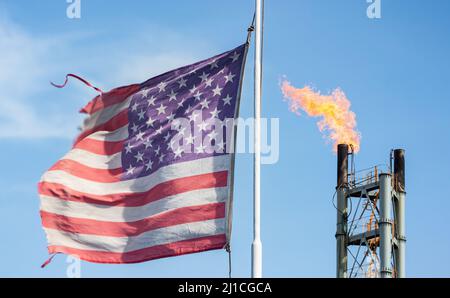 USA-Flagge mit Kamin der Gasanlage. Energiekrise, Russland Ukraine Konflikt, Krieg Großbritannien, Europa Gasversorgung, Lebenshaltungskrise Stockfoto