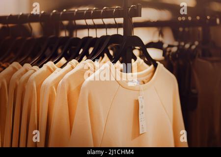 In einem Bekleidungsgeschäft hängen schöne weiche Freizeitkleidung an schwarzen Kleiderbügeln mit Preisschild. Einkaufen. Kleidung kaufen. Verkauf. Stockfoto