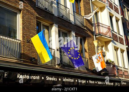 Nahaufnahme verschiedener lokaler und internationaler Flaggen (Ukraine-Flagge, EU-Flagge, Düsseldorf-Flagge) vor einem Restaurant in der Düsseldorfer Altstadt. Stockfoto