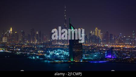 Dubai, VAE - 05 2021. Dez.: Nachtansicht des Burj Al Arab und der Dubai Marina mit dem Burj Khalifa in der Ferne Stockfoto