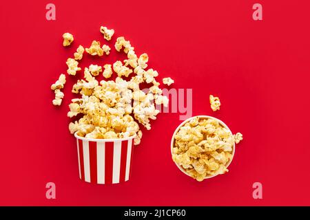 Zwei gestreifte runde Schachtel mit Popcorn auf hellrotem Hintergrund. Draufsicht, Platz für Text kopieren Stockfoto