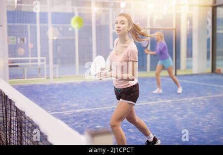 Frau, die beim Padel auf dem Platz den Ball servierte Stockfoto