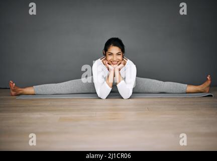 Sie werden erstaunt sein, was Ihr Körper erreichen kann. Porträt einer attraktiven jungen Frau, die die Splits in ihrer Yoga-Routine macht. Stockfoto