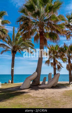 Die Open-Hand-Skulptur von Charo Garcia, die 2015 errichtet und in einen Palmenhain am Strand von Los Boliches, Fuengirola eingebettet wurde. Stockfoto