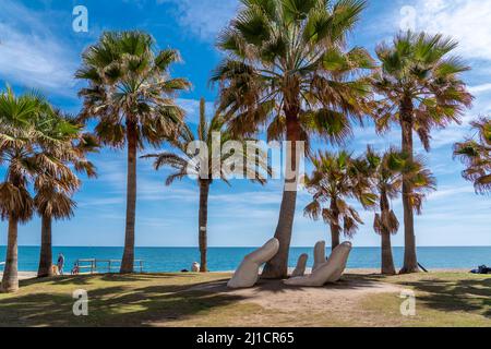 Die Open-Hand-Skulptur von Charo Garcia, die 2015 errichtet und in einen Palmenhain am Strand von Los Boliches, Fuengirola eingebettet wurde. Stockfoto