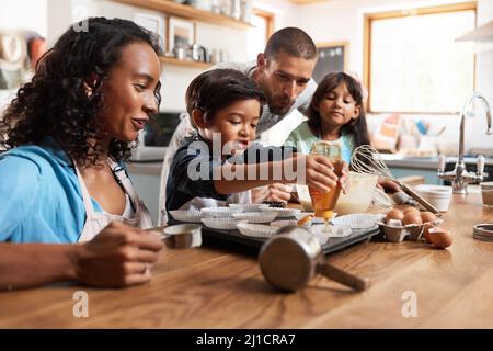 Ich möchte etwas mehr Honig in meinem. Eine kleine Aufnahme eines jungen Paares, das mit seinen beiden Kindern zu Hause backt. Stockfoto