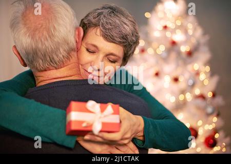 Seinen Schatz auf Chirstmas verdirbt. Eine kurze Aufnahme eines glücklichen, reifen Paares, das sich nach dem Austausch von Weihnachtsgeschenken umarmt hat. Stockfoto