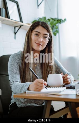 Mexikanische junge Frau arbeitet mit natürlichen Posen in ihrem Heimbüro Stockfoto