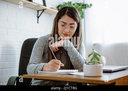 Mexikanische junge Frau arbeitet mit natürlichen Posen in ihrem Heimbüro Stockfoto