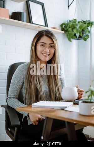 Mexikanische junge Frau arbeitet mit natürlichen Posen in ihrem Heimbüro Stockfoto