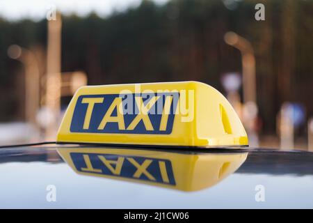 Nahaufnahme des Taxi-Schild auf einem Autodach. Tagsüber Verkehr Auf Dem Hintergrund. Stockfoto