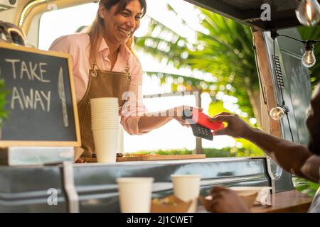 Fröhliche schwarze Frau, die im Café für Kaffee bezahlt Stockfoto