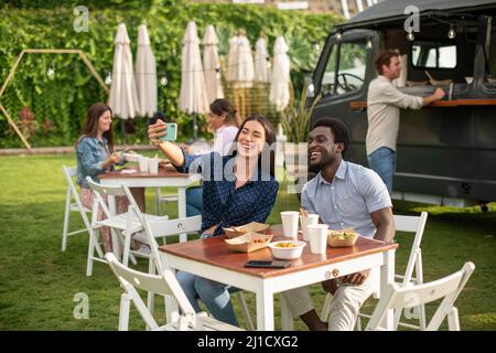 Diverse Freunde, die im Van frühstücken Stockfoto