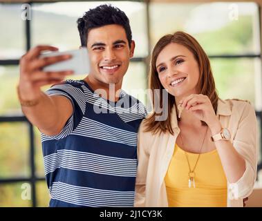 Sie machen bereits Erinnerungen in ihrem neuen Zuhause. Aufnahme eines glücklichen jungen Paares, das am Tag ein Selfie bei ihrem Umzug macht. Stockfoto